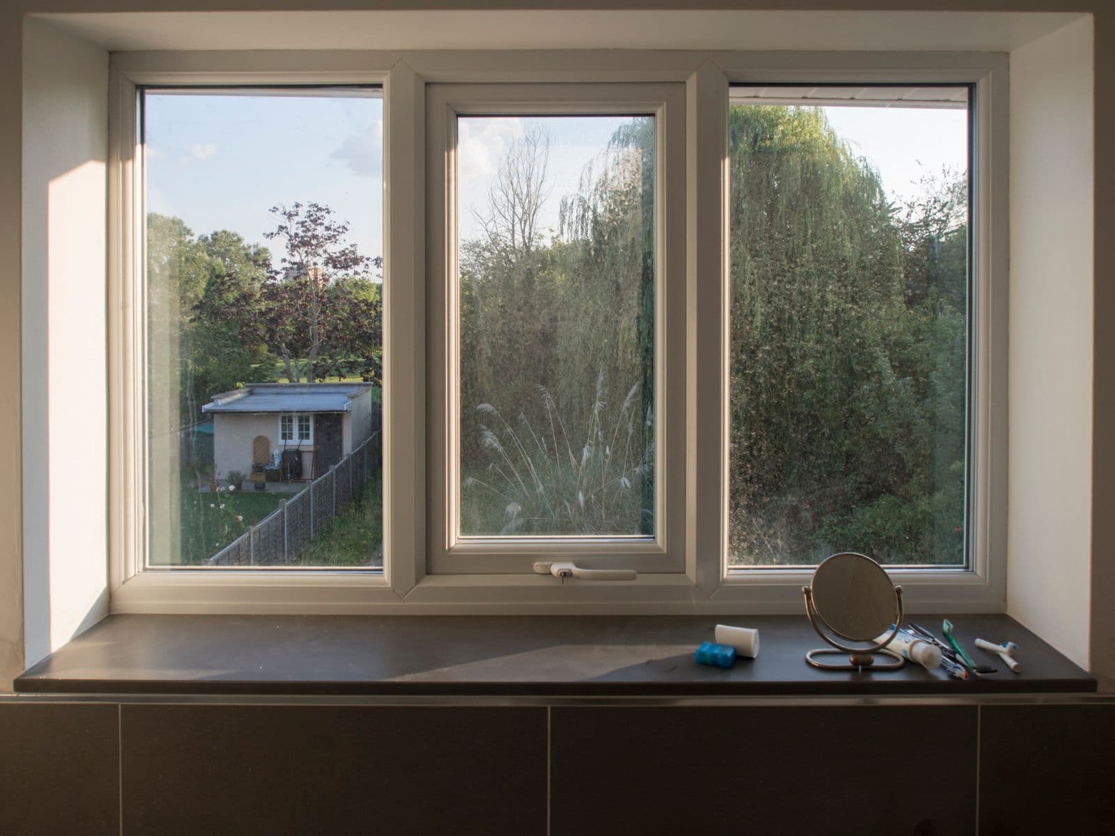 White-framed modern window looking out to a garden, illustrative product reference